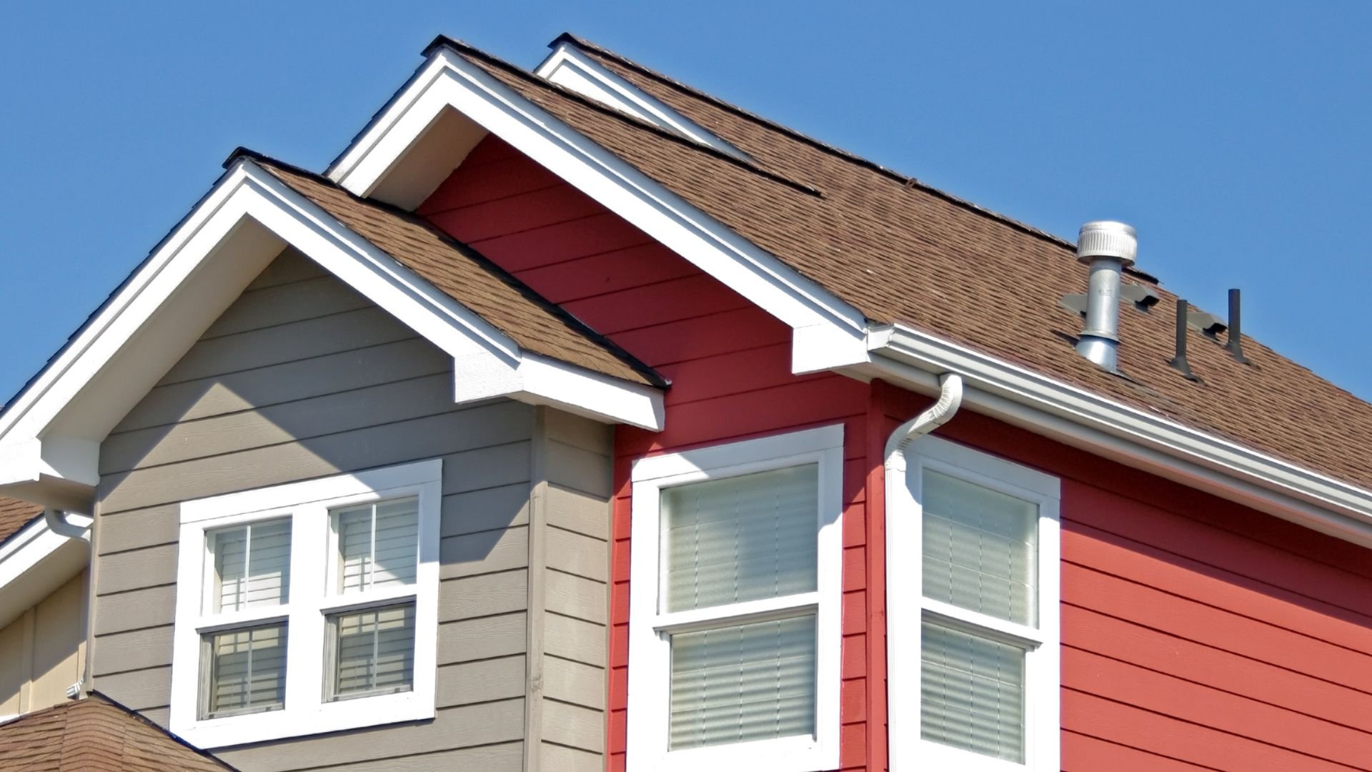 Modern house with gray and red siding, white trim, and brown roof